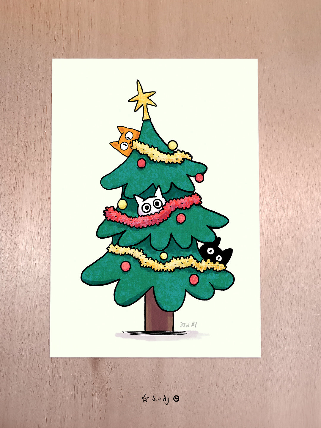 un sapin de noël décoré dans lequel trônent 3 petits chats cachés qui regardent fixement.