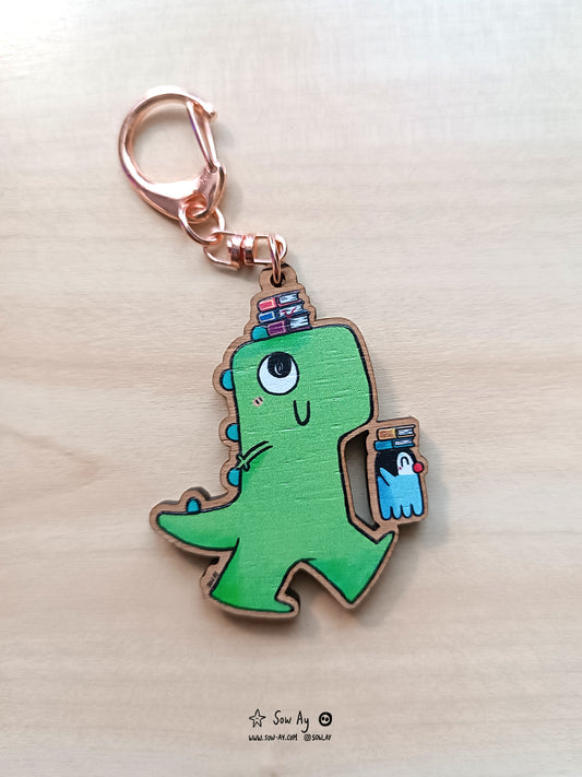 Un petit dinosaure vert tout content qui se promène avec son ami pingouin. Ils sont de profil, ils marchent et chacun d'entre eux porte une pile de livres sur leurs têtes.
