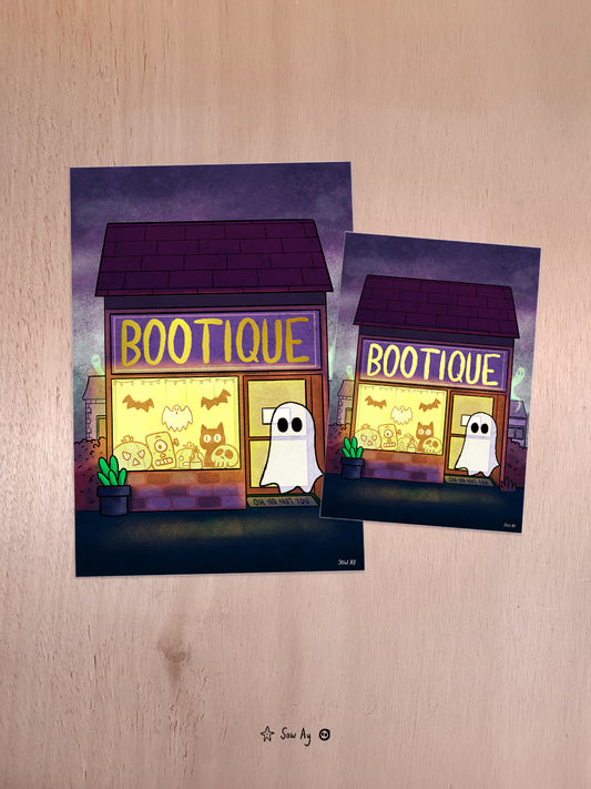 Un petit bâtiment est ouvert de part la lumière jaune que l'on voit. En vitrine, il y a des petits éléments type Halloween. La boutique s'appelle "Bootique" et un fantôme se tient devant.