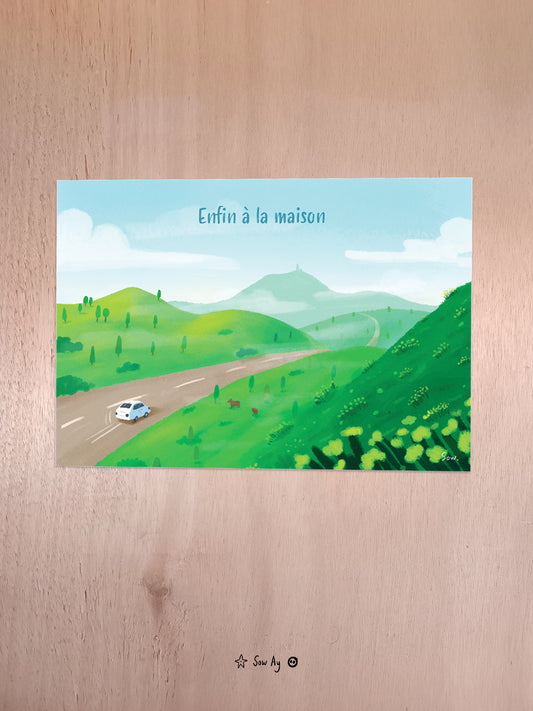 On voit de haut la campagne avec des vaches, ainsi qu'une route sur laquelle roule une petite voiture blanche. Au loin, on aperçoit le puy-de-dôme et il est noté "enfin à la maison".