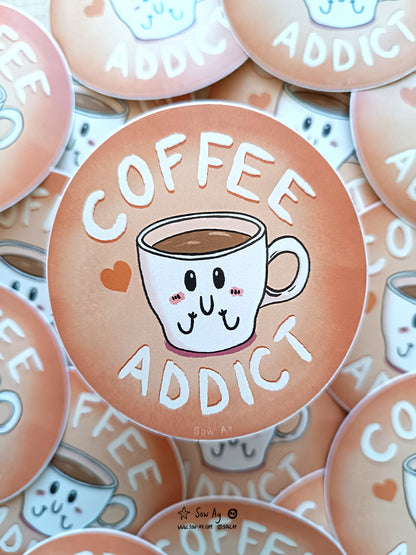 une petite tasse à café, toute contente et rougissante. Autour d'elle est écrit "coffee addict"