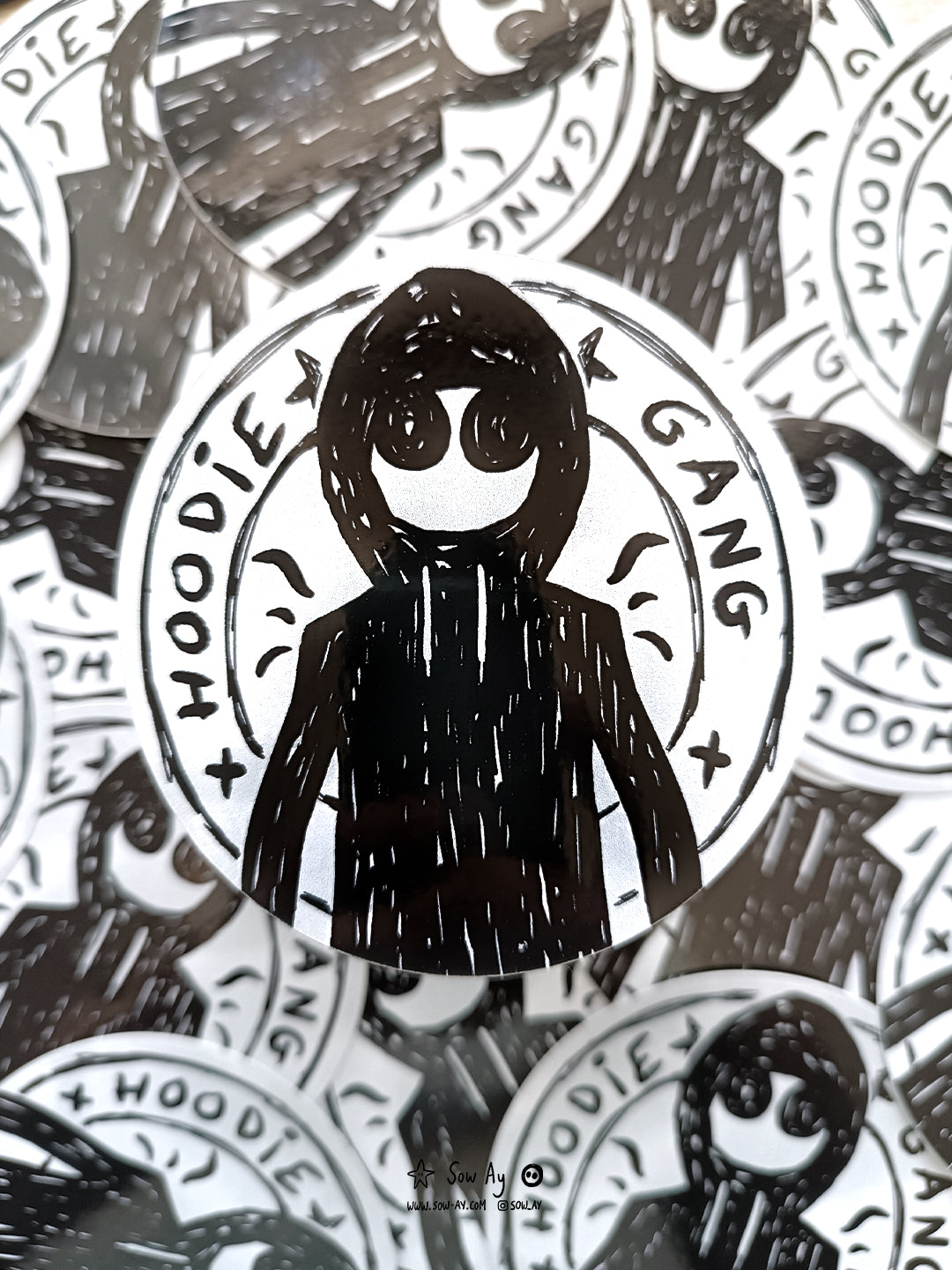 personnage de face avec un sweat shirt à capuche et de grands yeux. Autour de lui est inscrit : hoodie gang