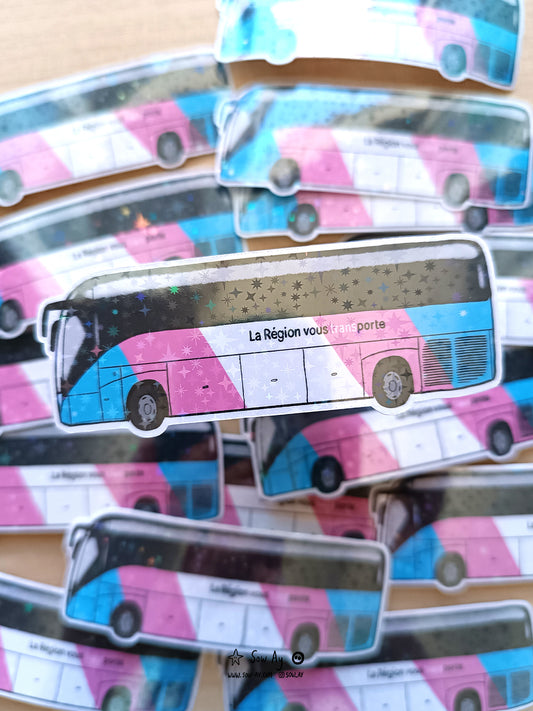 bus de profil de la région auvergne rhônes alpes aux couleurs du drapeau transgenre bleu rose et blanc, sur lequel est écrit en noir "la région vous transporte" et "trans" est écrit en blanc et se détache