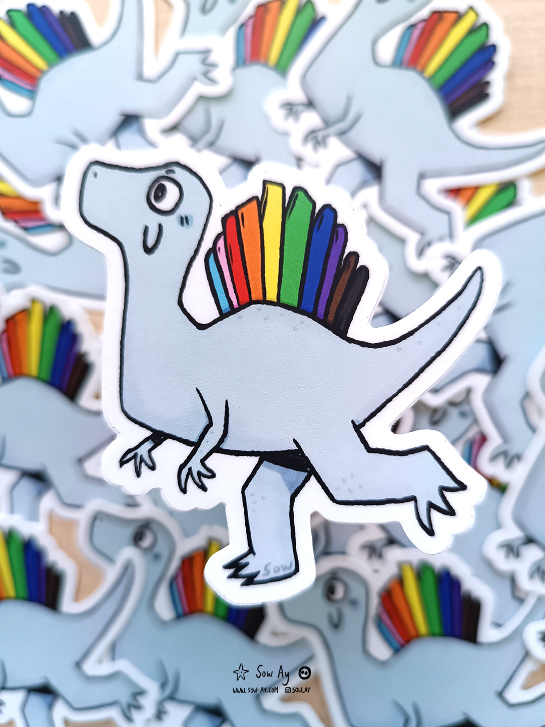 dinosaure de profil, spinosaure gris avec crête dorsale aux couleurs du drapeau GBTQIA+